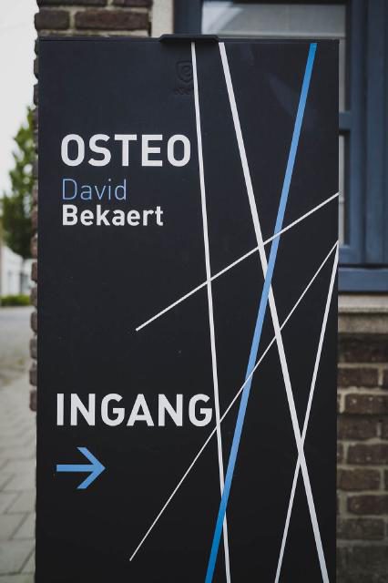Bord aan de straatkant dat de ingang van de praktijk aanduidt